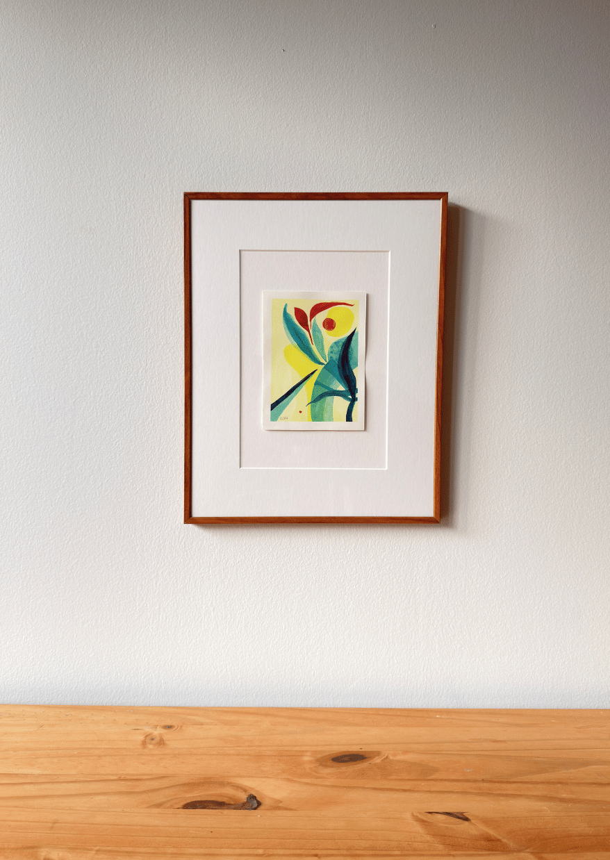 Framed artwork on a white wall above a wooden surface