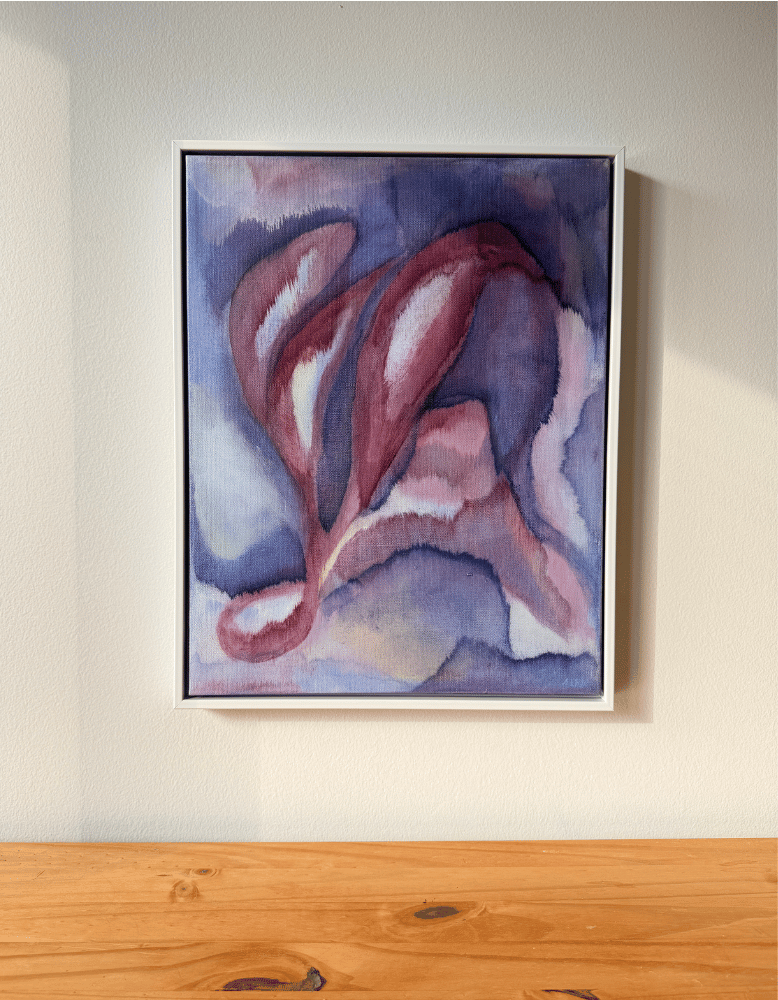 Framed abstract painting on a wall above a wooden surface