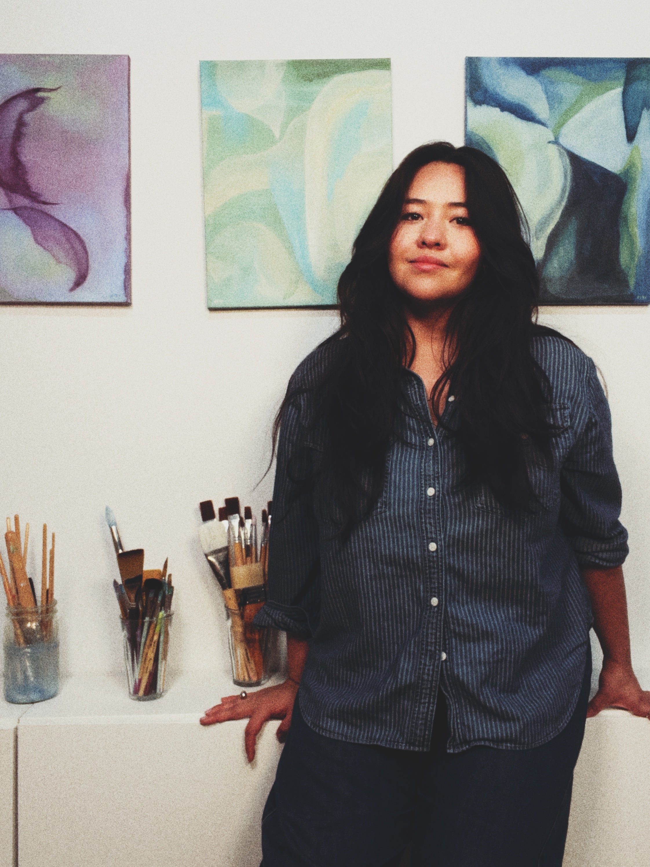 Woman standing in an art studio with paintings on the wall