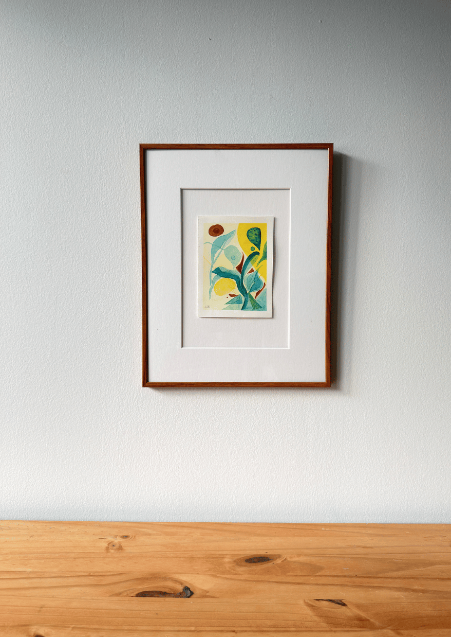 Framed artwork on a white wall above a wooden surface