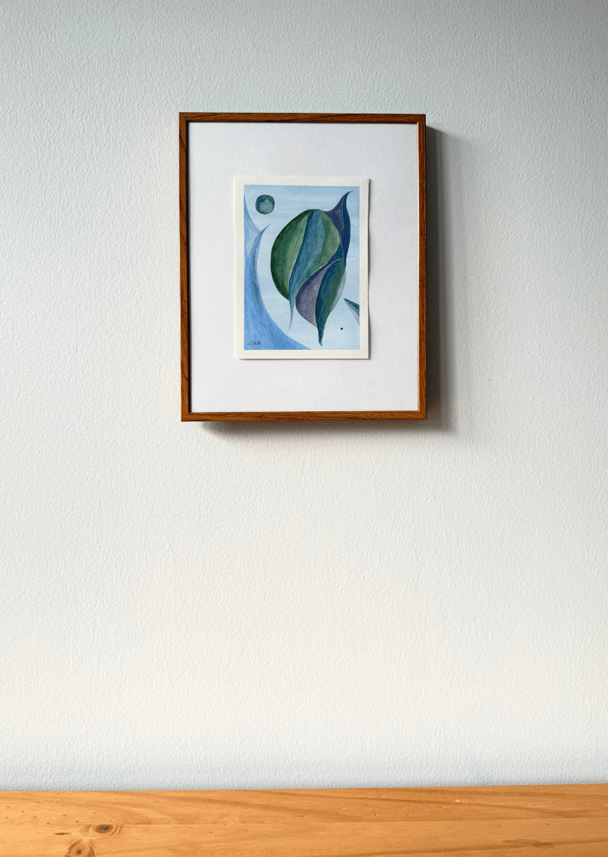 Framed artwork on a white wall with a wooden baseboard.