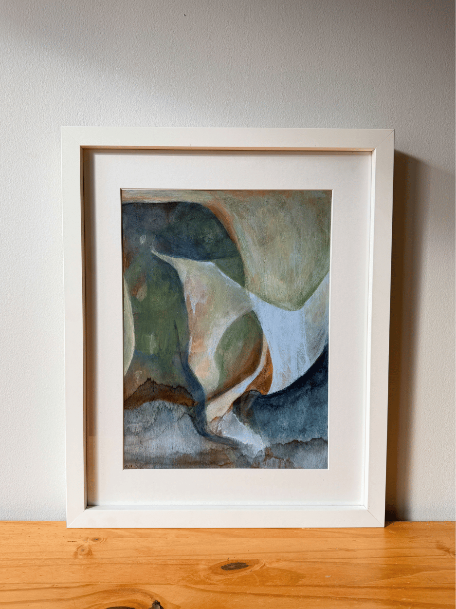 Framed abstract art piece on a wooden surface with a neutral background