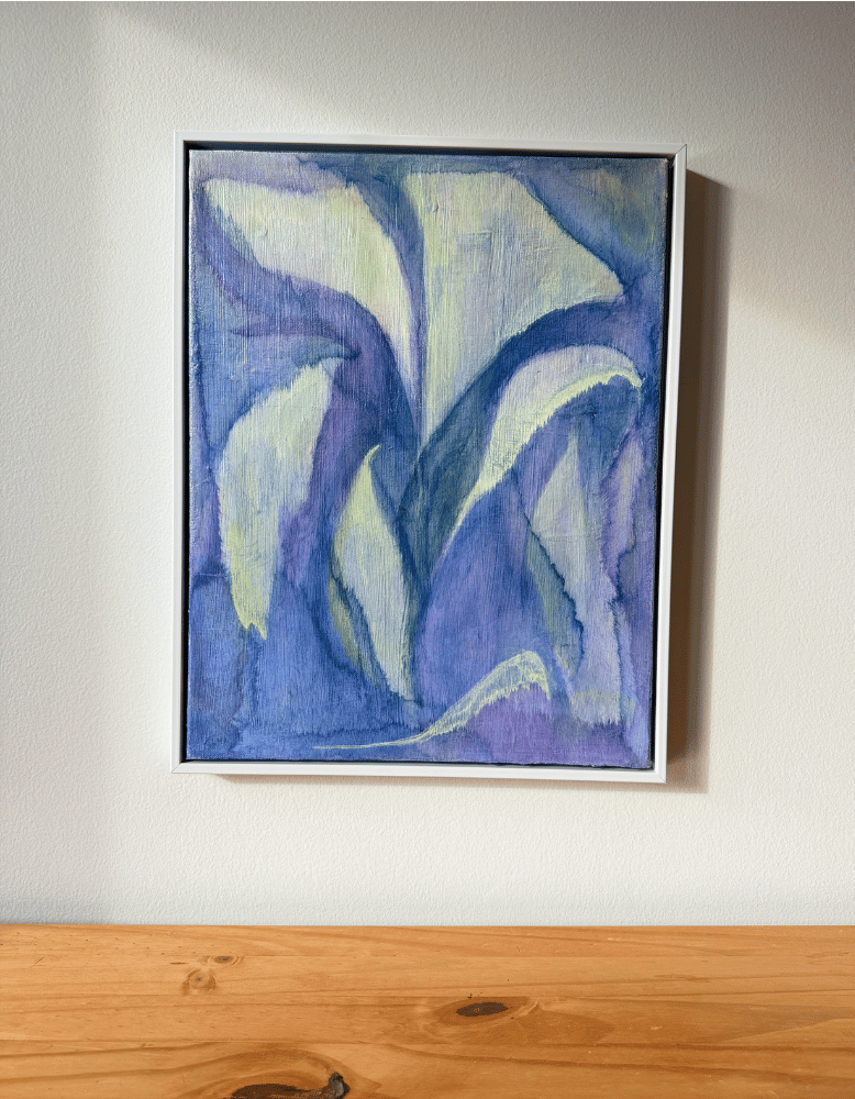 Framed abstract painting with blue and white hues on a plain wall.