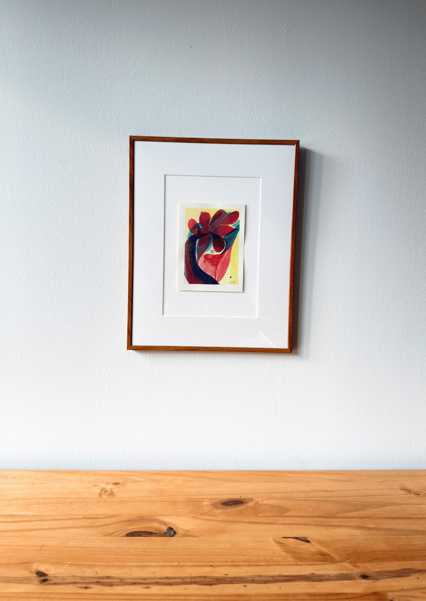 Framed artwork on a white wall above a wooden surface